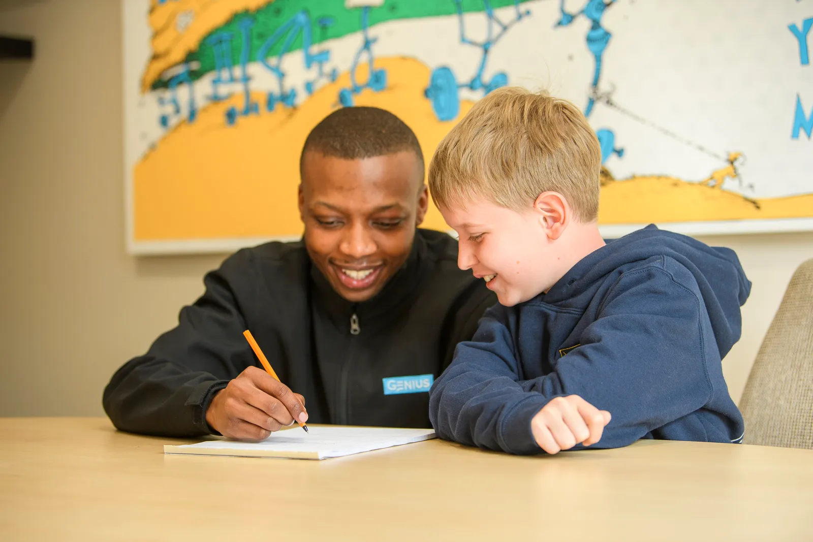 A Genius tutor writing alongside an engaged young learner